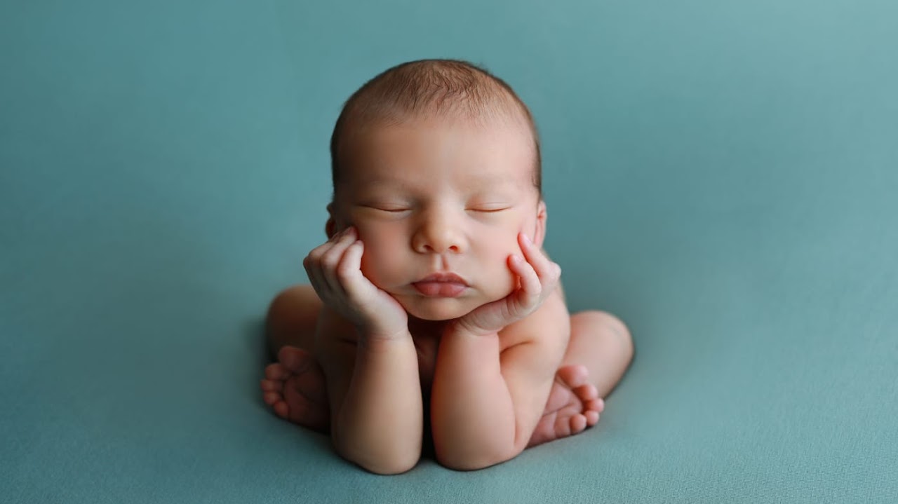 Sleeping newborn on teal backdrop
